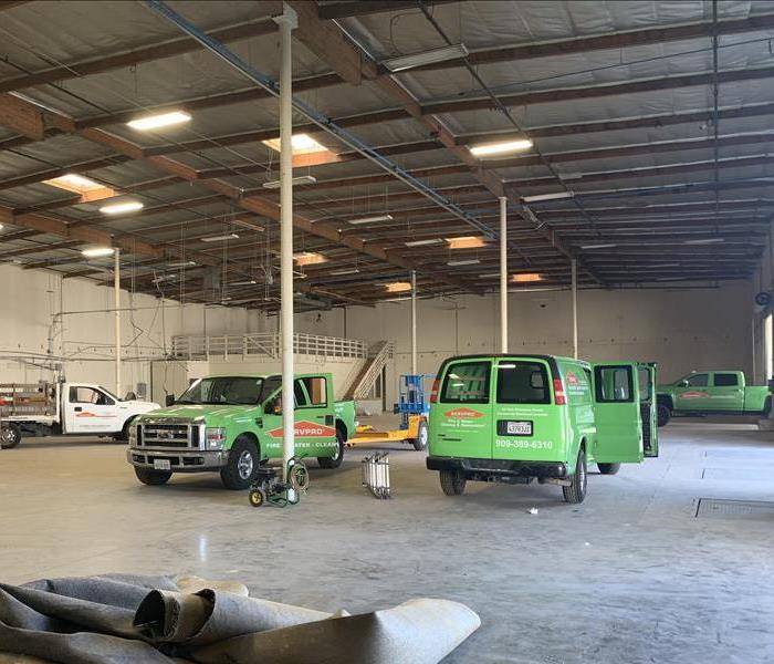 SERVPRO vehicles parked inside a large and empty commercial warehouse.