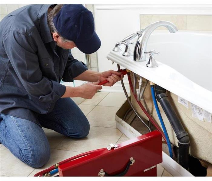 A plumber is checking the pipe of a bathtub