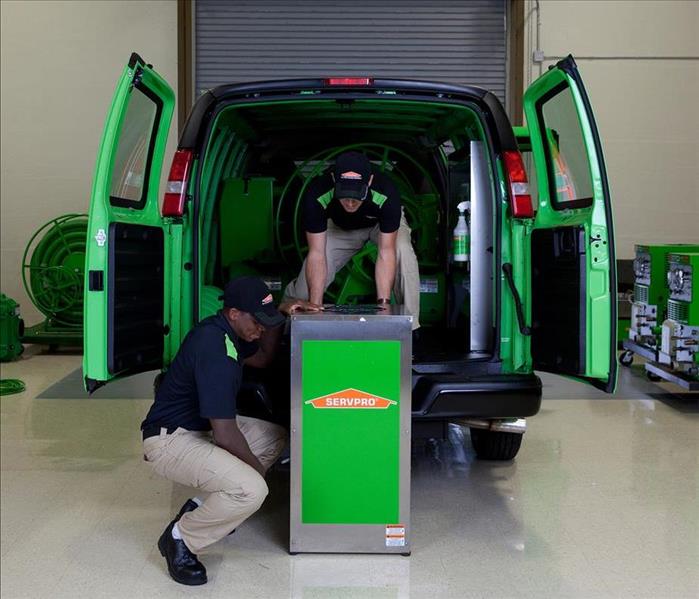 Two SERVPRO technicians trying to get equipment inside a van